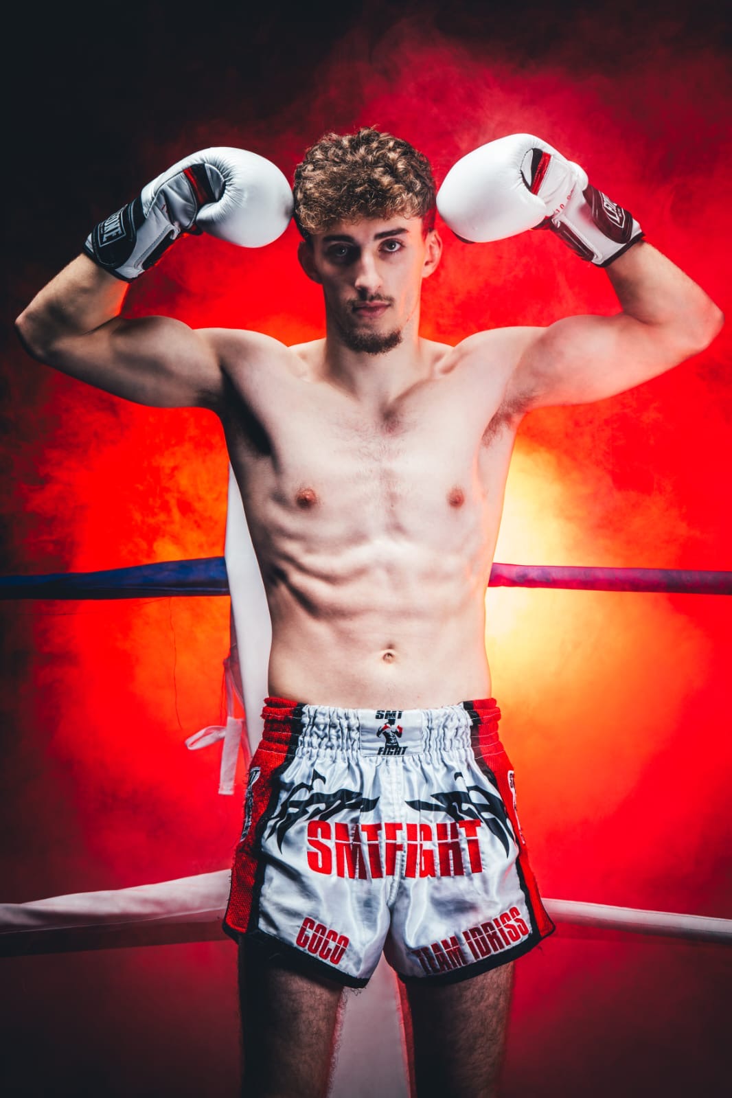 Photo de Corentin dans le ring portant ses gants de boxe, levant les poings en signe de victoire